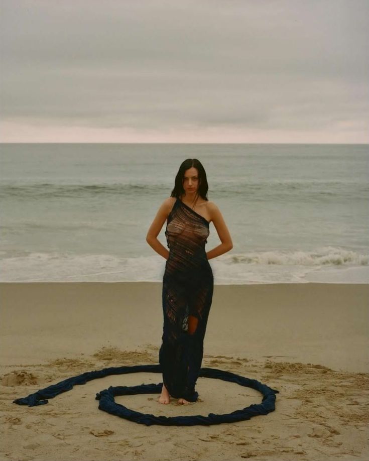 a woman is standing on the beach with her hands on her hips