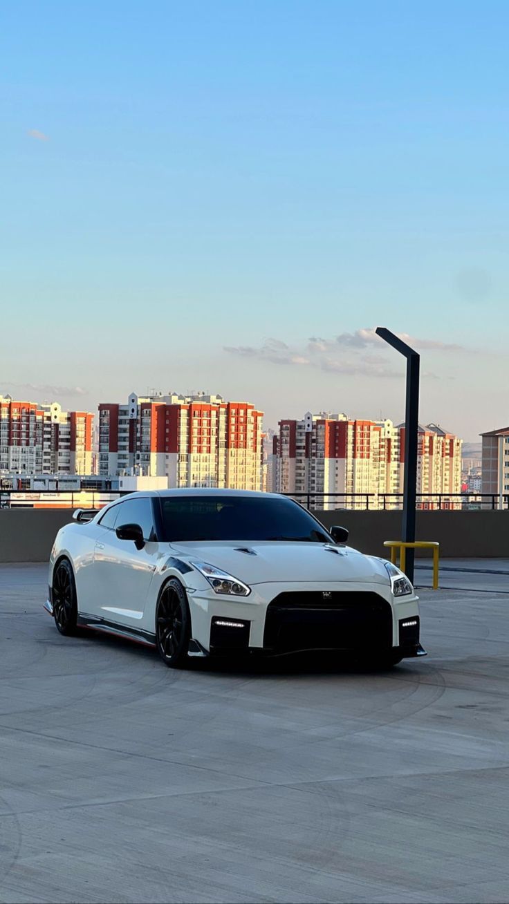 a white sports car parked on top of a parking lot next to a tall building