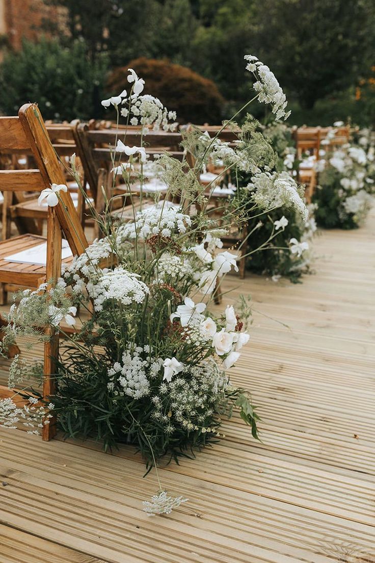 some white flowers and chairs on a wooden deck in the middle of an outdoor area