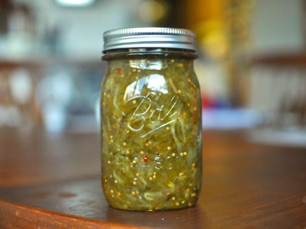 a jar filled with pickles sitting on top of a wooden table