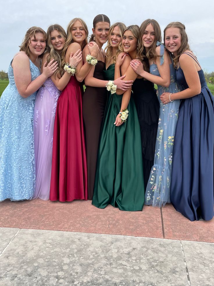 a group of young women standing next to each other in long dresses posing for the camera