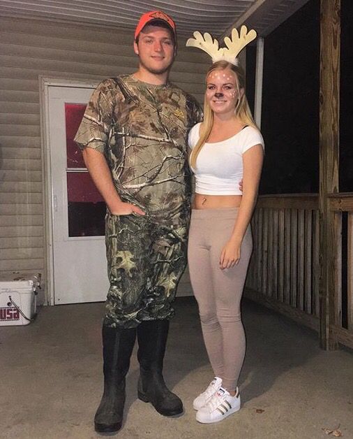 a man and woman dressed up as deer antlers standing in front of a house