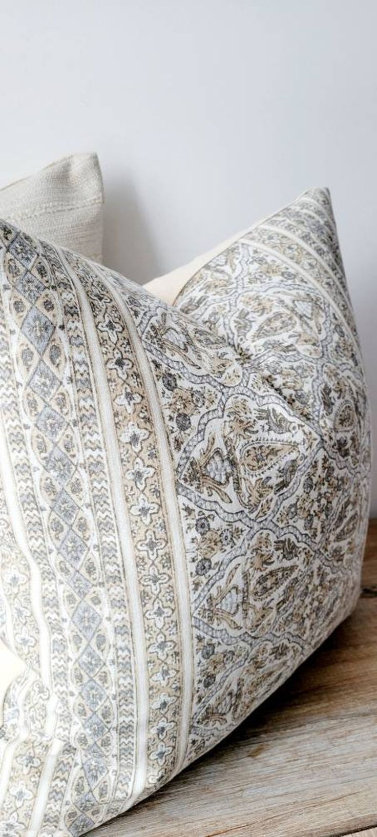 a white and grey pillow sitting on top of a wooden table next to a wall