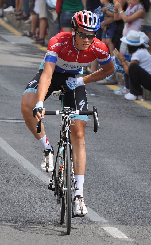 a bicyclist is riding down the street in front of a large crowd