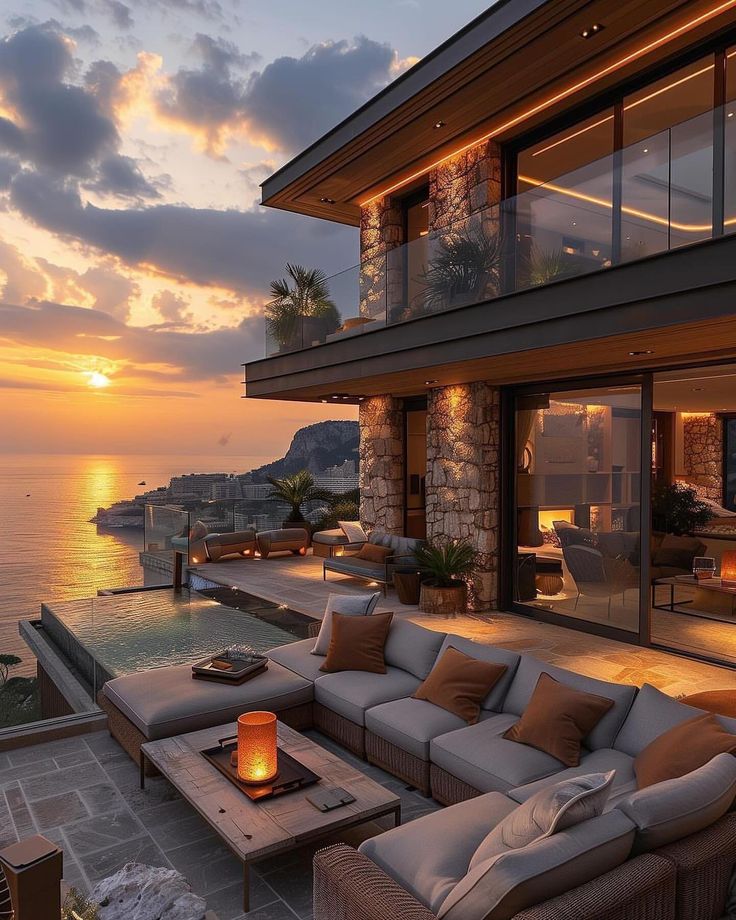 an outdoor living area overlooking the ocean at sunset