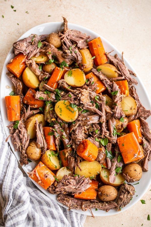 a white plate topped with roast, potatoes and carrots on top of a table