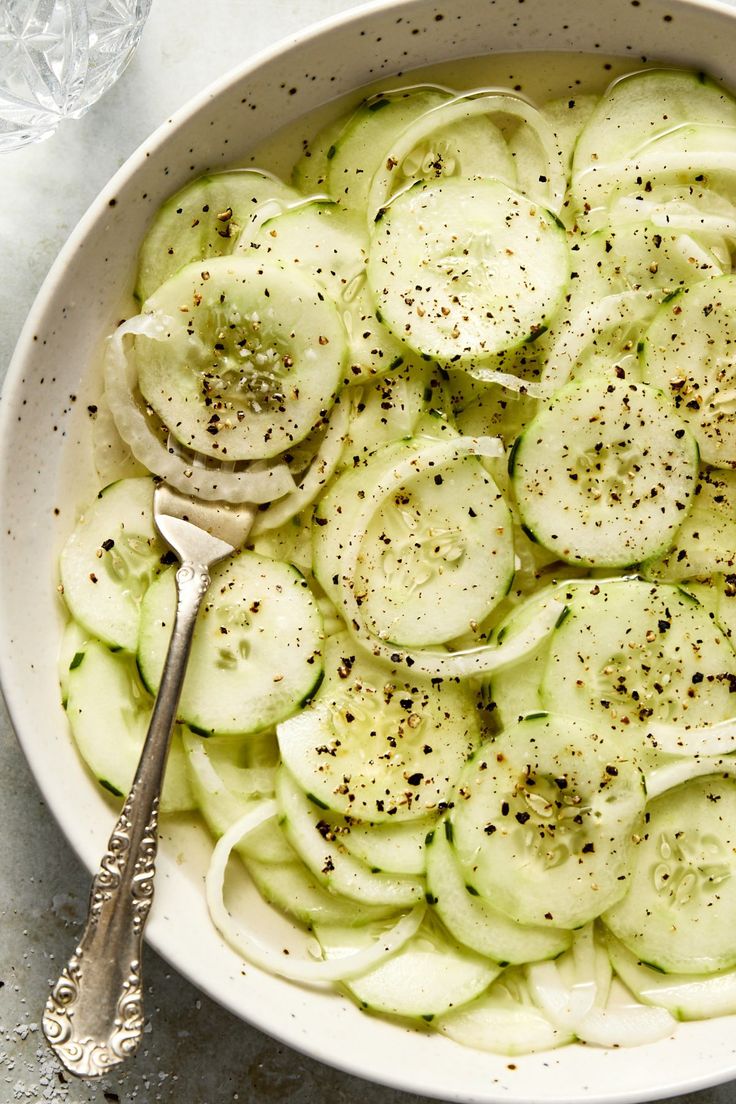 a bowl filled with sliced cucumbers and seasoning