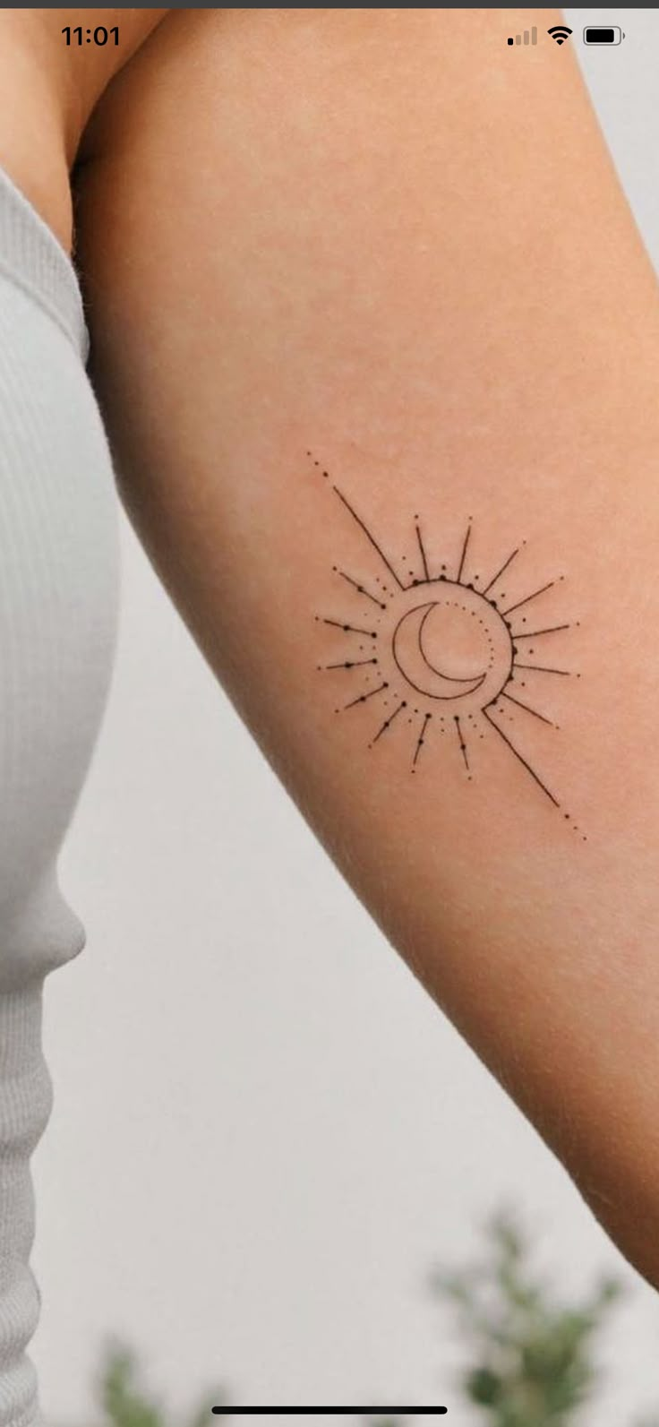 a woman's arm with a small sun and moon tattoo on the back of it