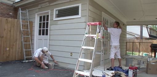 two men are painting the outside of a house