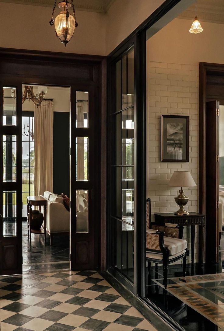 a living room with black and white checkered flooring, chandelier and glass doors