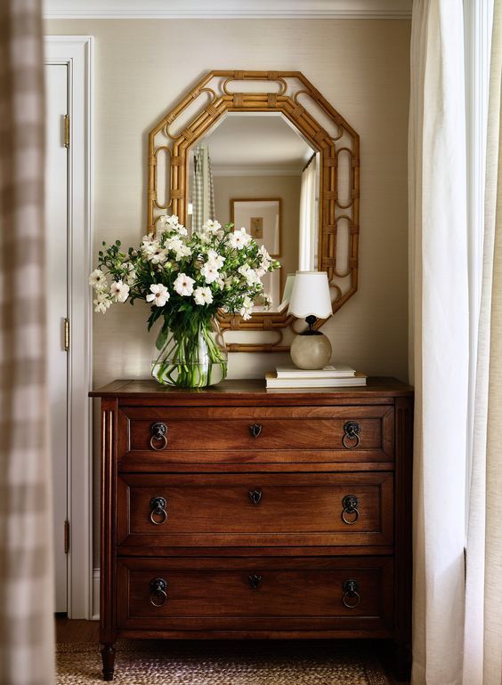 a dresser with flowers and a mirror on top