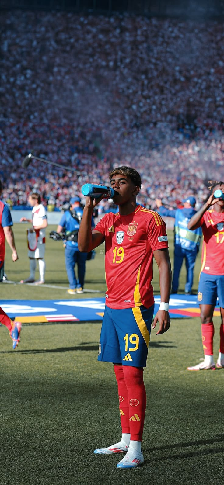 a soccer player is standing on the field with his head in his hand and other players behind him