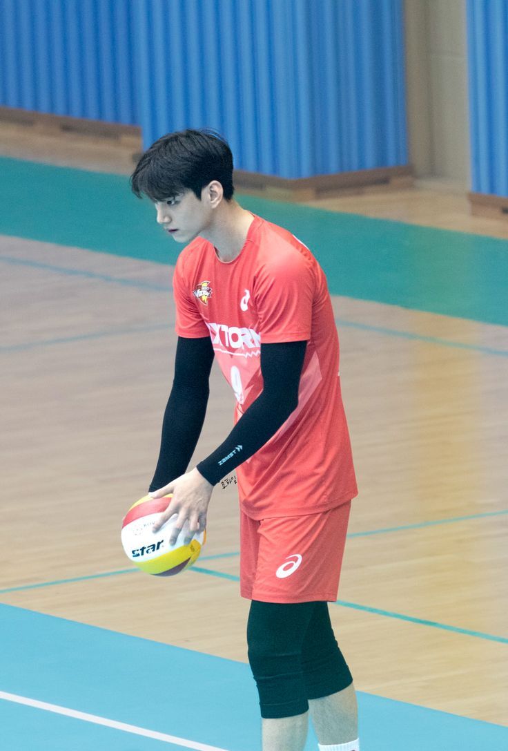 a man holding a yellow and white frisbee in his hand on a court