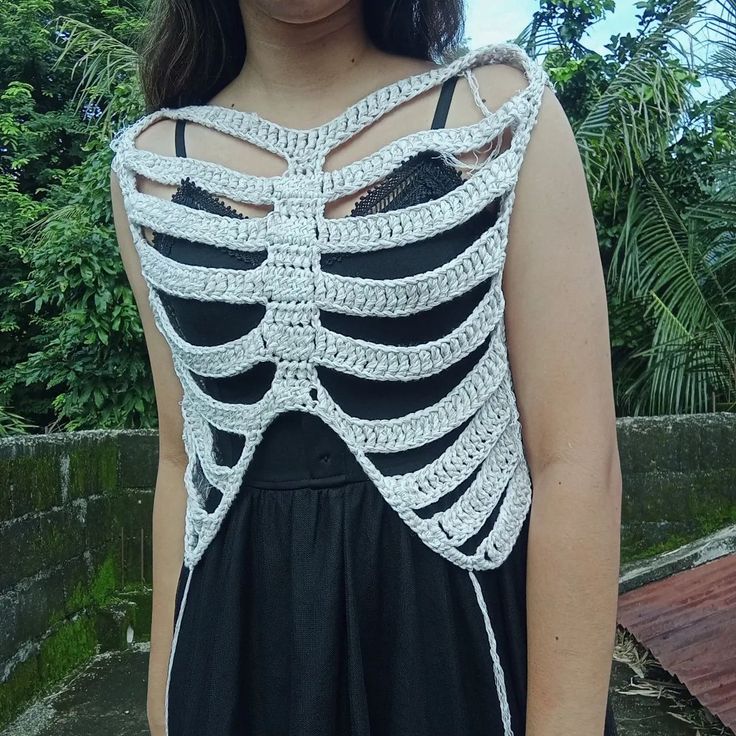 a woman wearing a black dress with a white crochet skeleton on it's back