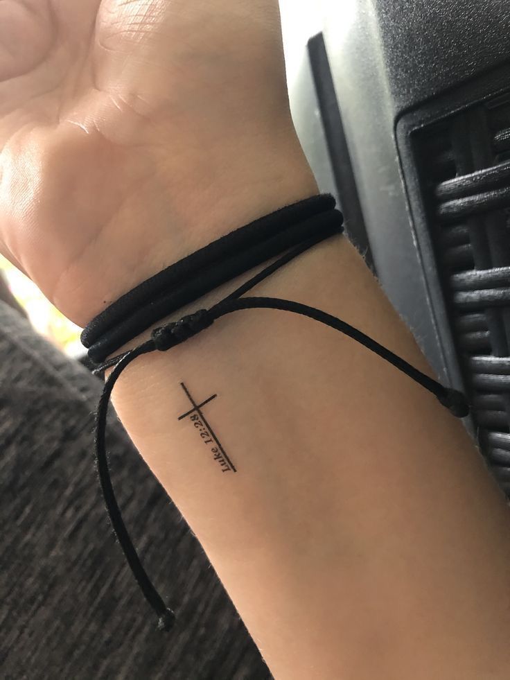 a woman's arm with a cross tattoo on the left side of her wrist