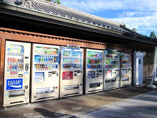 a row of vending machines sitting next to each other on a side walk in front of a building