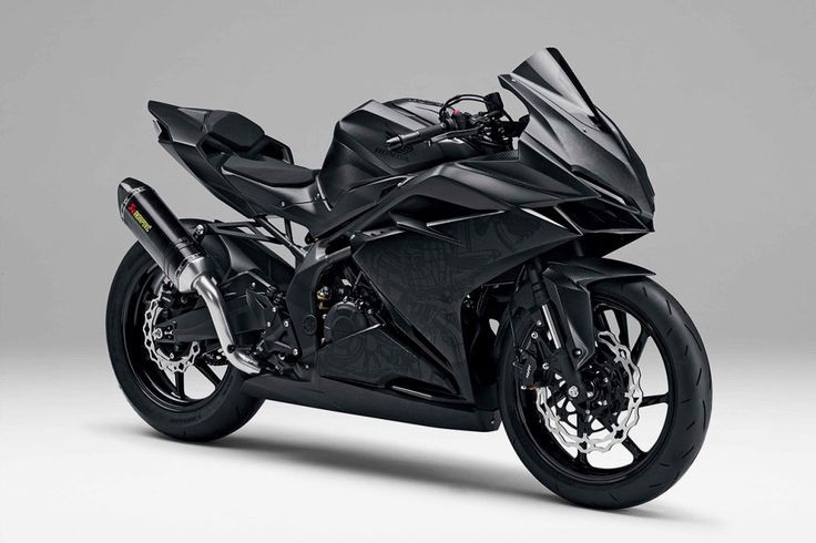 a black motorcycle parked on top of a white floor in front of a gray background