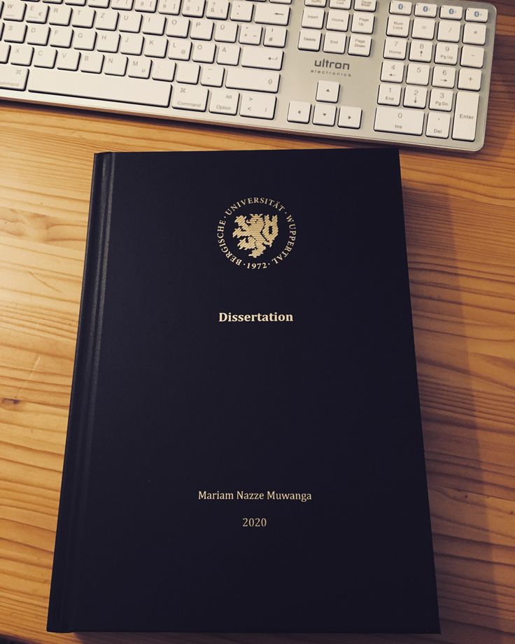 a black book sitting on top of a wooden desk next to a keyboard and mouse