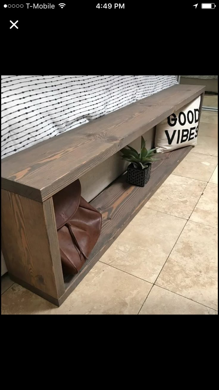 a wooden bench sitting on top of a tiled floor next to a planter and pillow