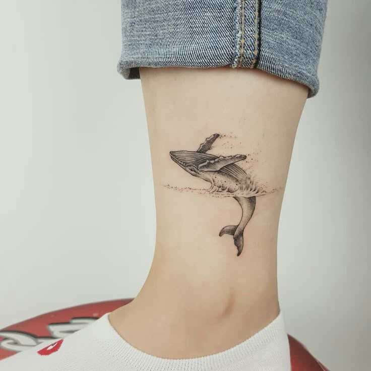 a woman's foot with a small shark tattoo on the side of her leg