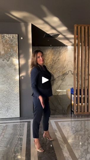 a woman standing in front of a marble wall