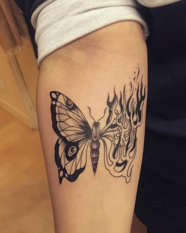 a woman's arm with a black and white butterfly tattoo on the left forearm