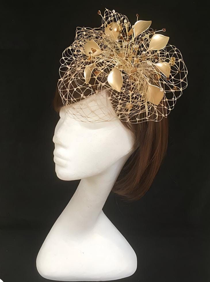 Delicate gold fascinator perfect for the guest who wants something fairly understated.  This design is a beautiful selection of glass effect leaves and flowers with an additional scatter of brown crystal and tan glacier stone, clustered together amongst a fine layer of veiling and set onto a fine comfort base tiara band. As with all our designs, this piece can be made exact to the image or in any colour combination to match in with your outfit. If a specific colour is required customers can mess Gold Fascinator For Royal Ascot And Formal Occasions, Gold Headpieces For Royal Ascot Formal Occasion, Gold Mini Hats For Royal Ascot Evening, Elegant Gold Mini Hat For Royal Ascot, Elegant Gold Costume Hats For Royal Ascot, Elegant Mini Hat For Royal Ascot In Gold, Gold Fascinator For Formal Royal Ascot, Gold Structured Crown Hat For Kentucky Derby, Gold Fascinator For Evening At Kentucky Derby