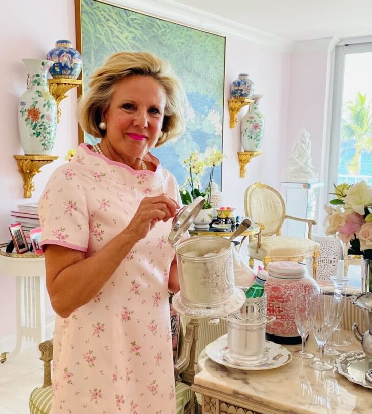 a woman standing in front of a table filled with cups and saucers