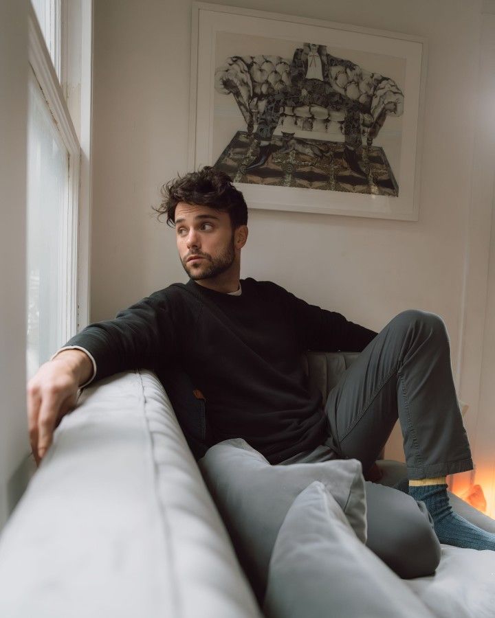 a man sitting on top of a couch next to a window