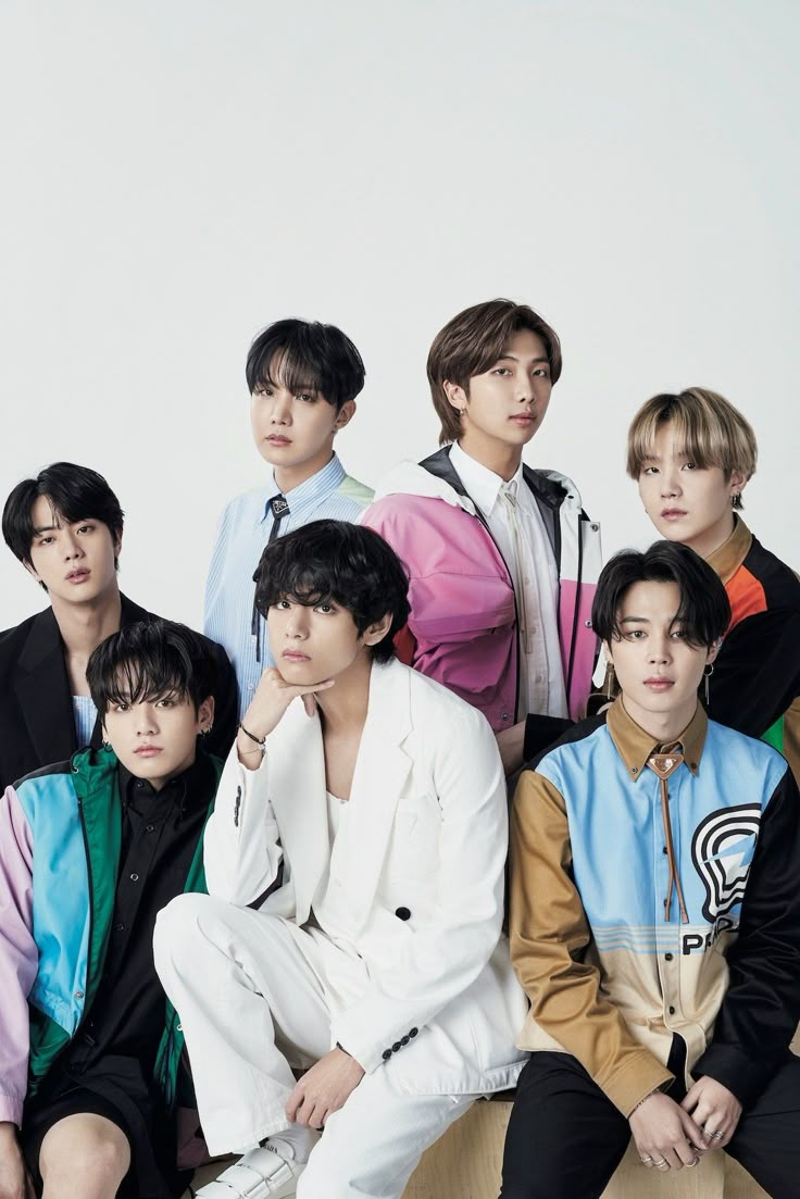 group of young men sitting next to each other in front of a white wall,