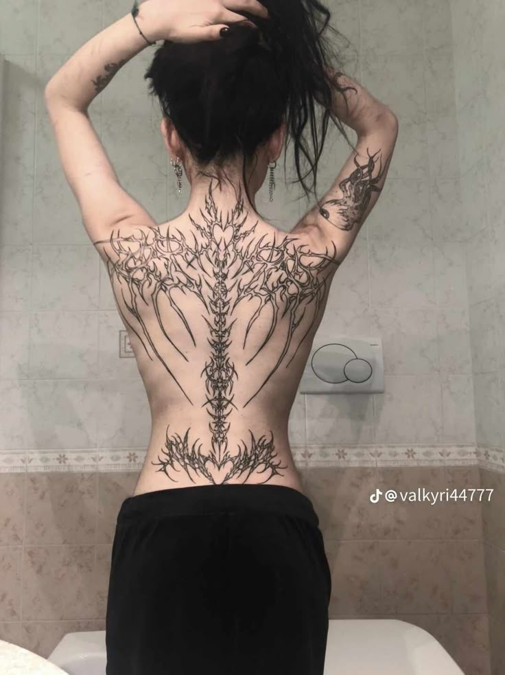 a woman with tattoos on her back standing in front of a toilet