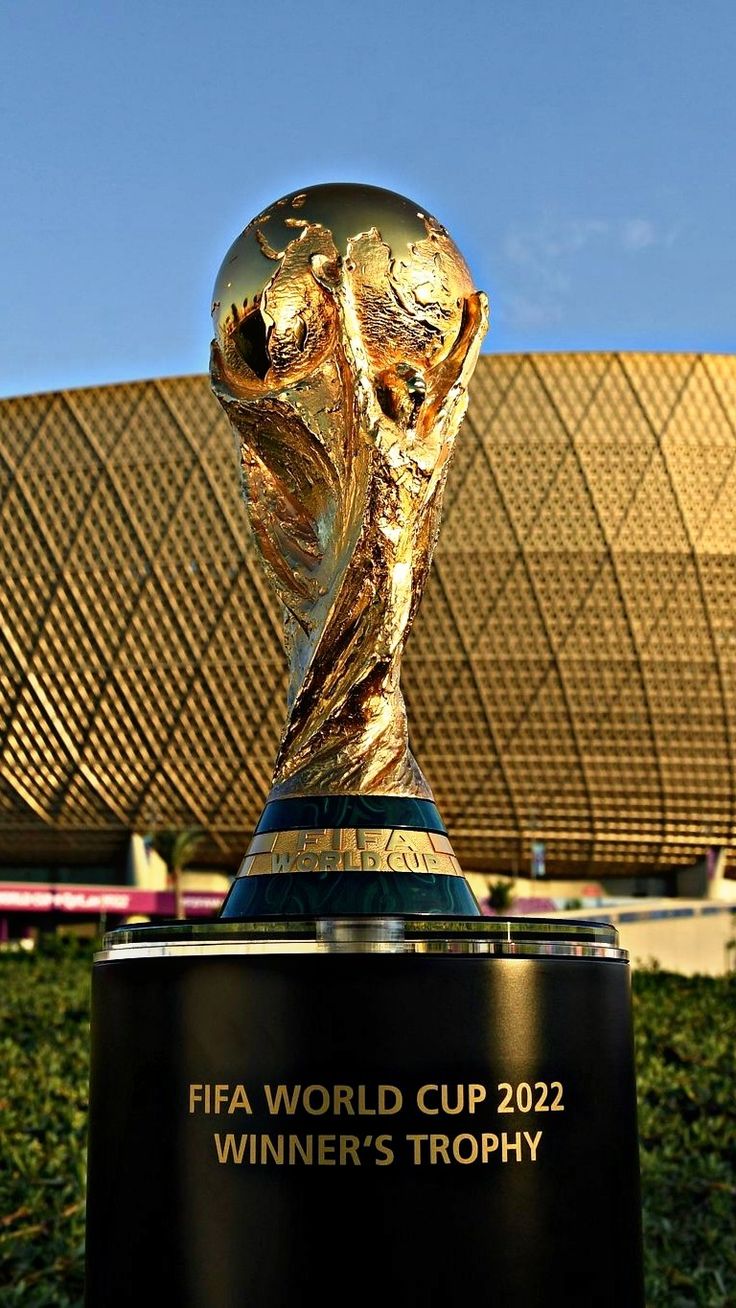 the world cup trophy is displayed in front of a building with grass and bushes around it