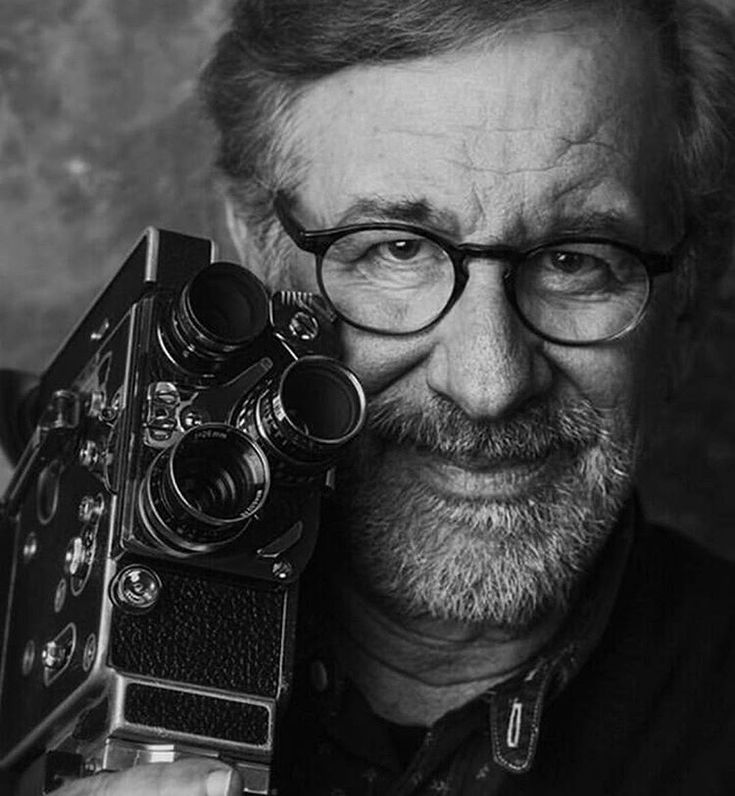 an old man with glasses holding a camera