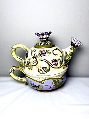 a ceramic tea pot sitting on top of a white tablecloth covered table next to a gray wall