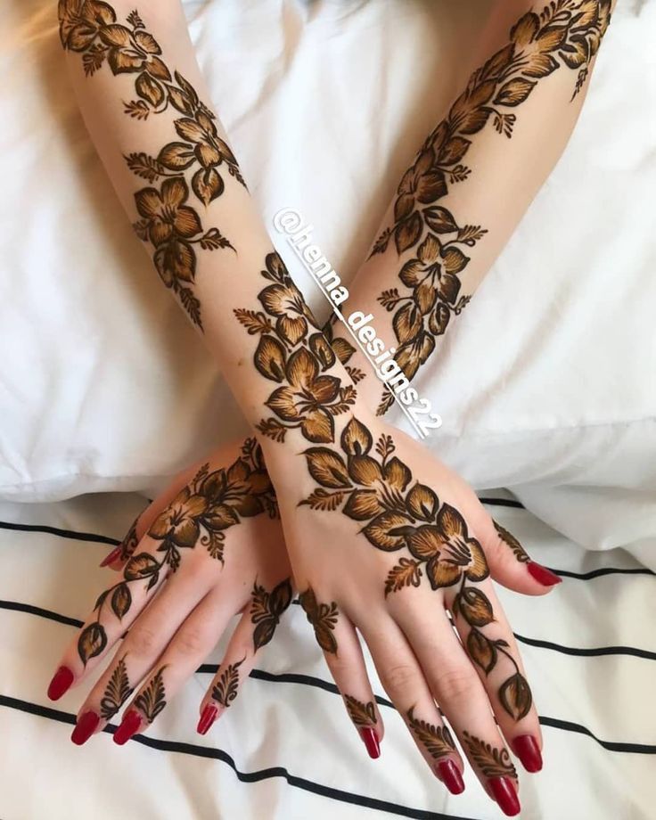 two hands with henna designs on them sitting on a white bedding covered in sheets