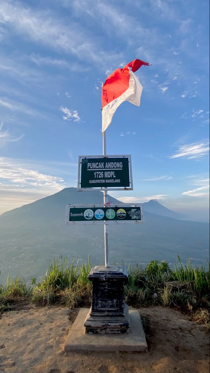 a sign on top of a mountain with a flag