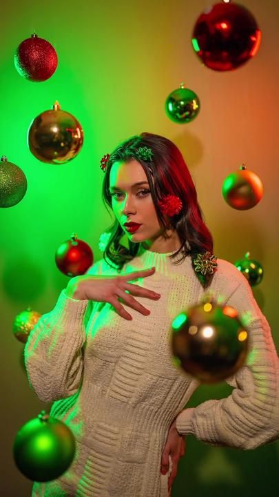 a woman in a white sweater surrounded by christmas ornaments and balls on a green background