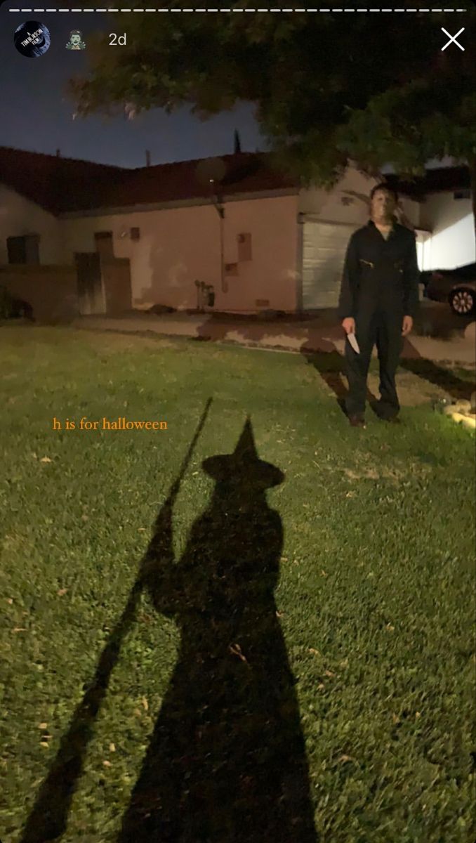 a man standing in the grass with a long shadow on it's back ground