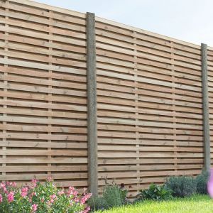 the fence is made of wood planks and has purple flowers in front of it