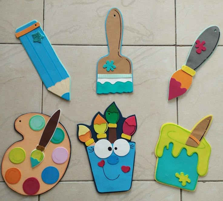 colorful wooden cut outs with paintbrushes, paints and brushes on the tile floor