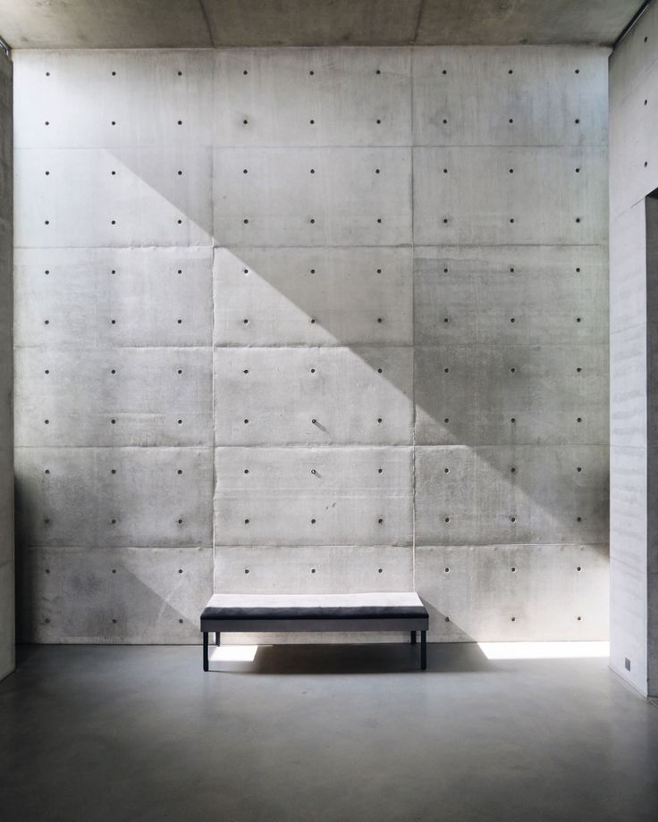 an empty room with concrete walls and a bench