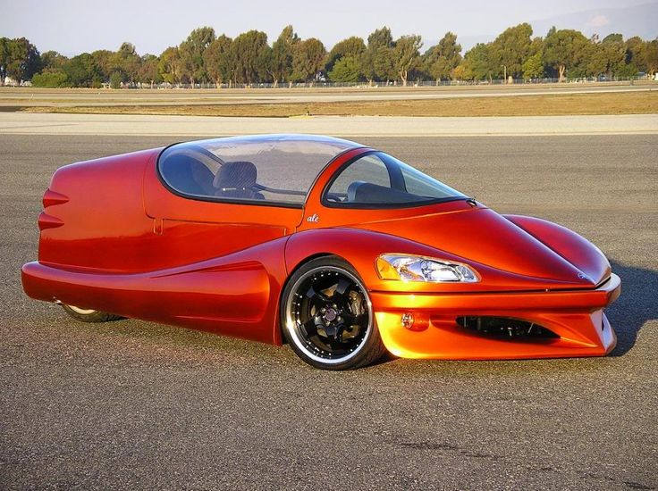 an orange sports car parked on the side of a road with trees in the background