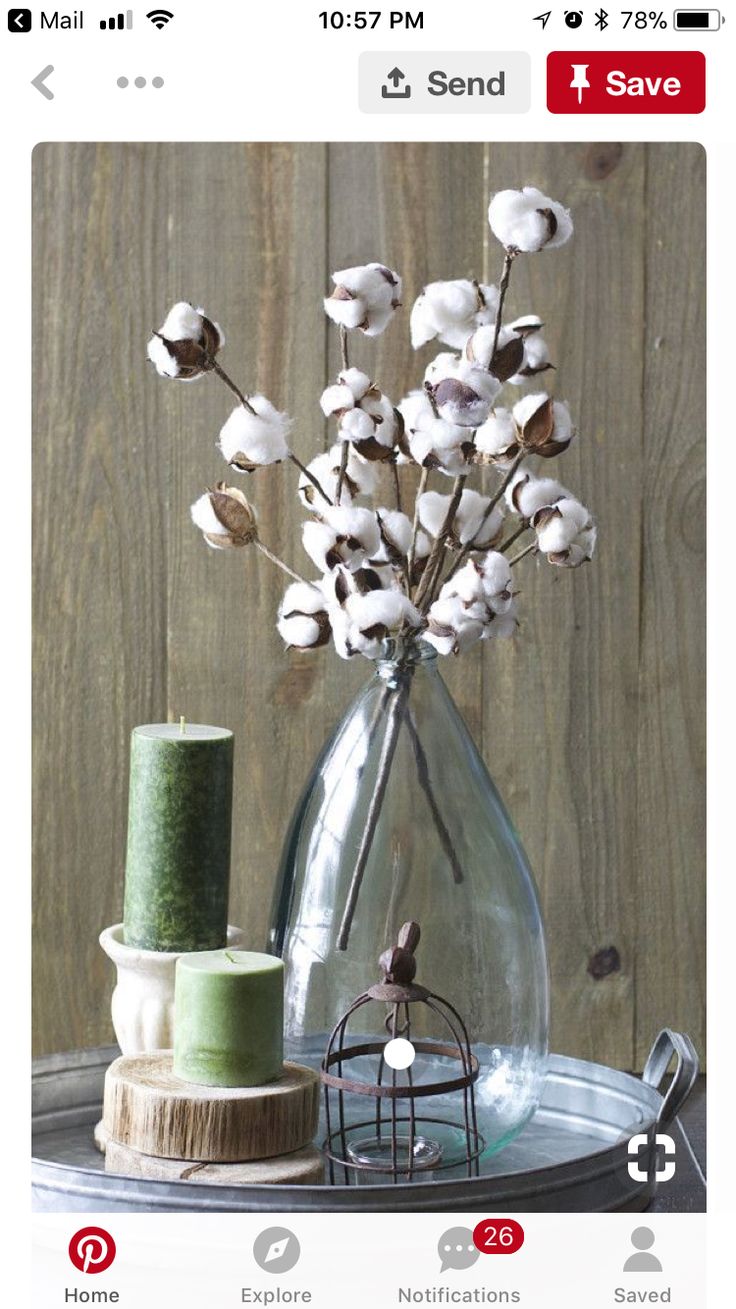 a vase filled with white flowers sitting on top of a wooden table next to a thread spool