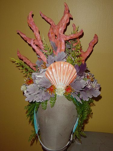 a vase filled with flowers and corals on top of a table next to a wall