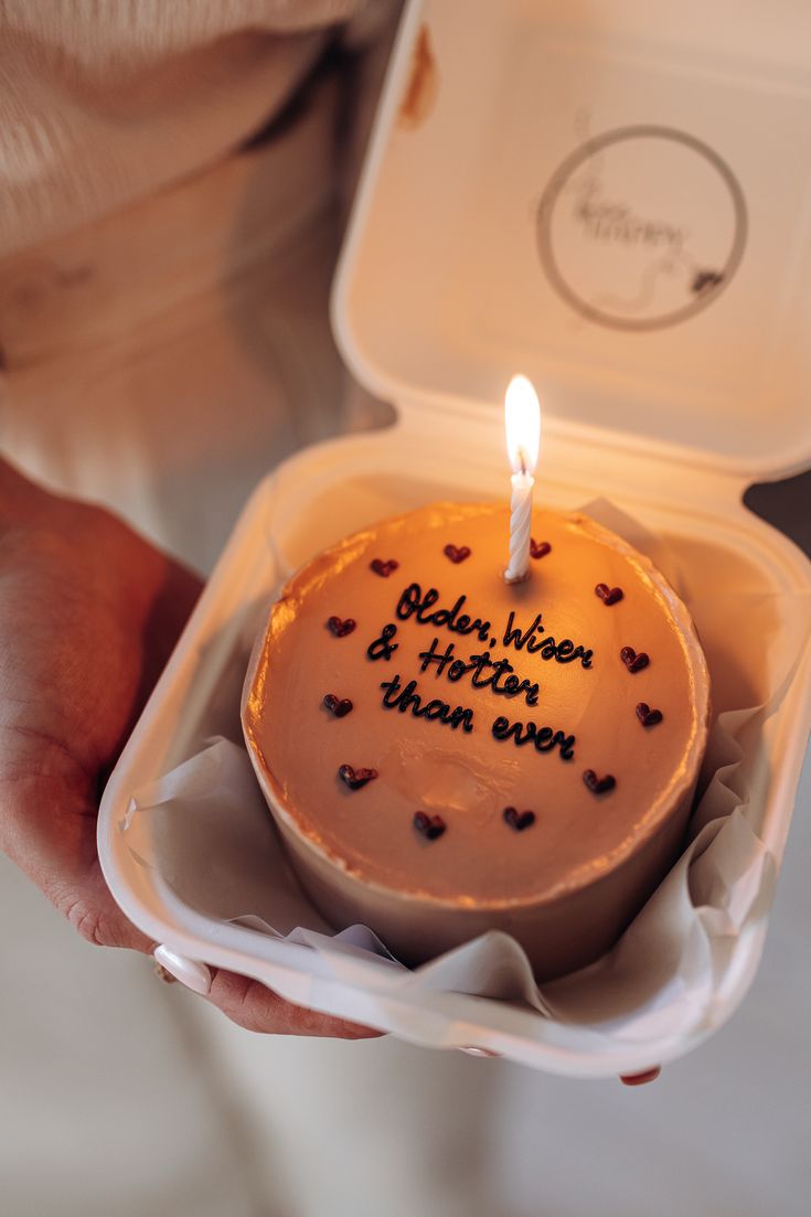 a person holding a cake with a candle in it