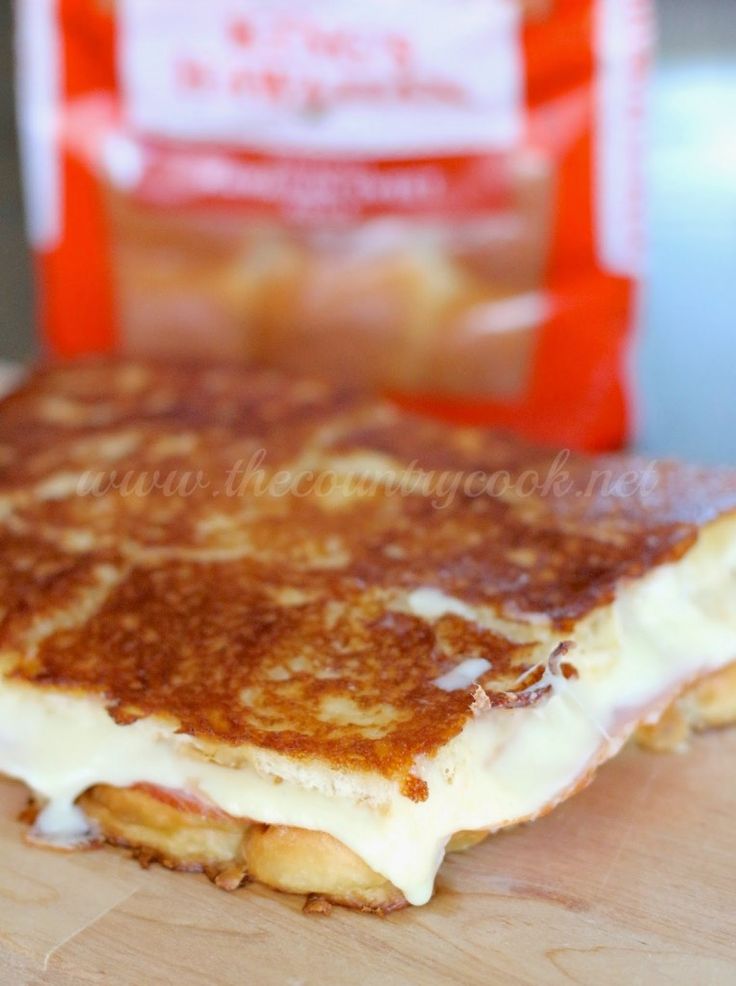 a grilled cheese sandwich sitting on top of a wooden cutting board next to a bag of chips