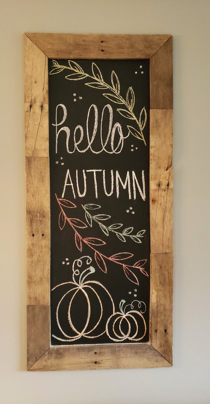 a chalkboard with autumn written on it in a wooden frame hanging on the wall