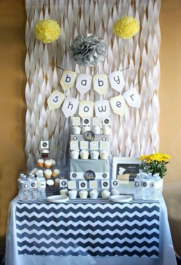 a baby shower party with blue, white and yellow decorations on the wall next to it