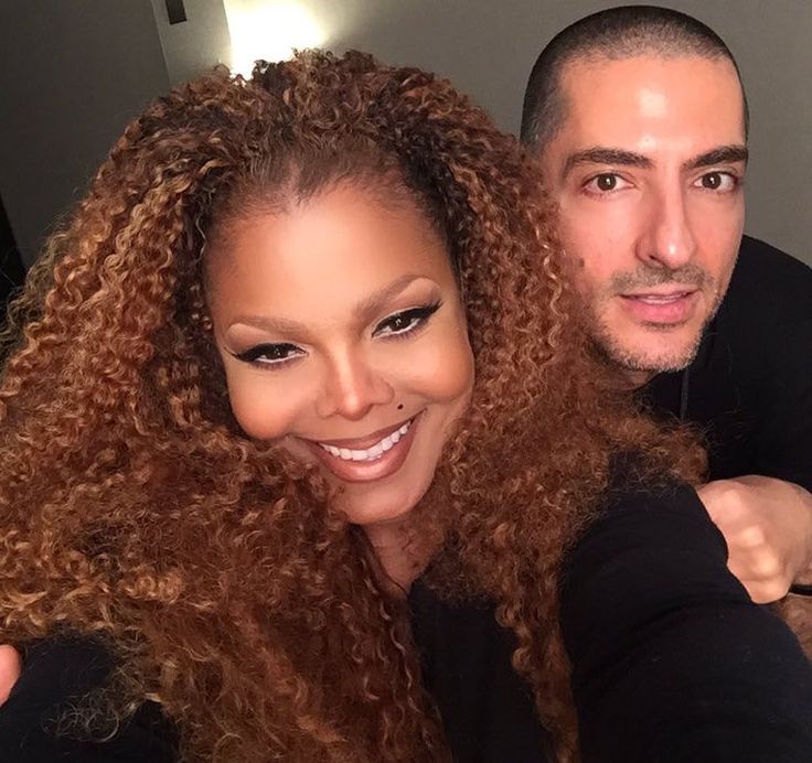 a man and woman posing for the camera with their arms around each other's shoulders