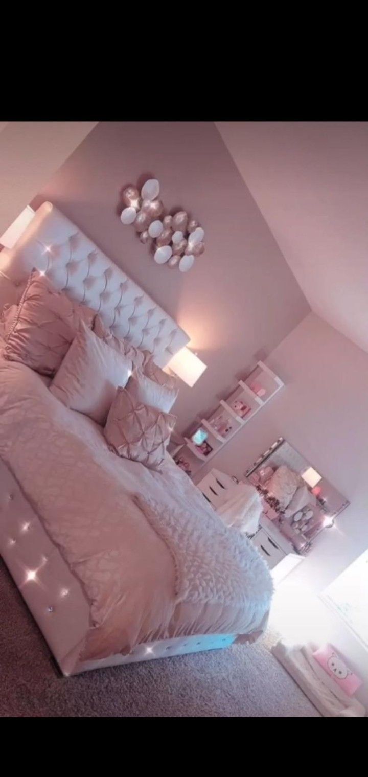 an instagramted photo of a bedroom with pink walls and white bedding, lights on the headboard